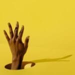 persons hand on yellow surface