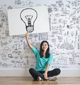 woman draw a light bulb in white board