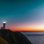 sunset sky over sea and lighthouse located on hill