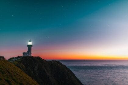 sunset sky over sea and lighthouse located on hill