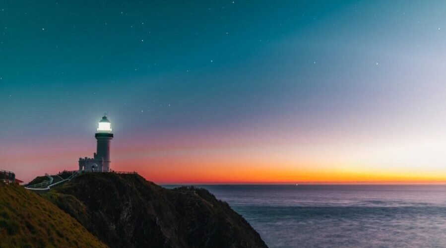 sunset sky over sea and lighthouse located on hill