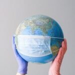 hands with latex gloves holding a globe with a face mask