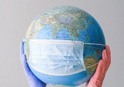 hands with latex gloves holding a globe with a face mask