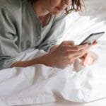 woman using smartphone in bed