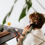 busy female talking on smartphone and checking messages during work in contemporary office