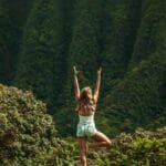 anonymous woman standing in vrksasana pose while practicing yoga in nature