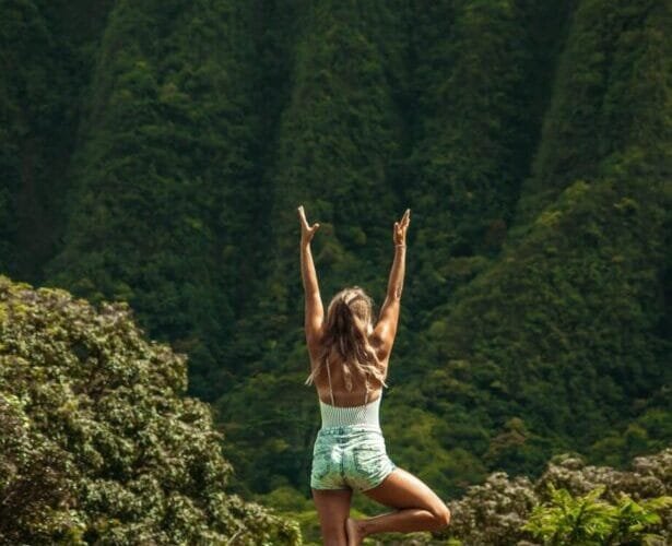 anonymous woman standing in vrksasana pose while practicing yoga in nature