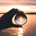 photo displays person holding ball with reflection of horizon