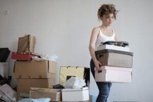 concentrated woman carrying stack of cardboard boxes for relocation
