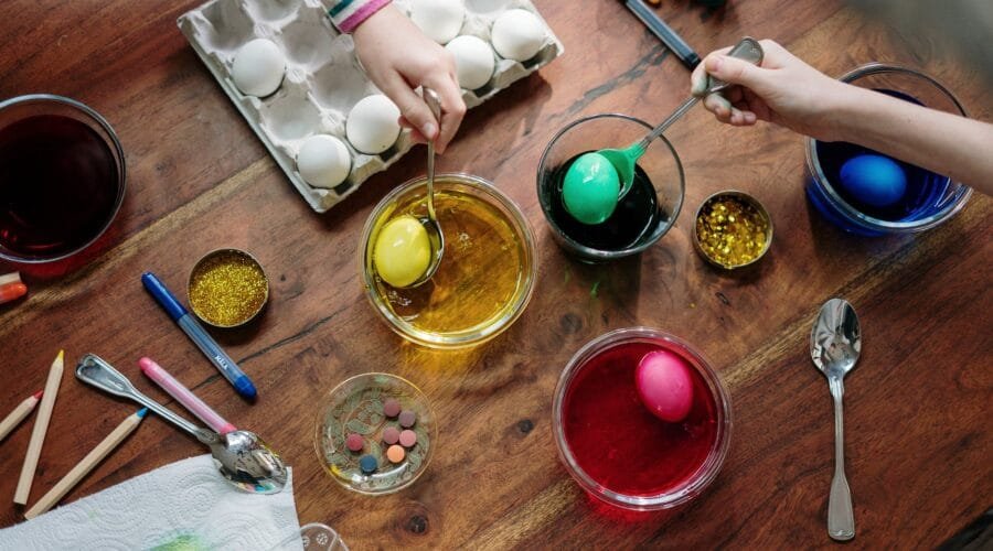 people holding silver spoons with colored eggs