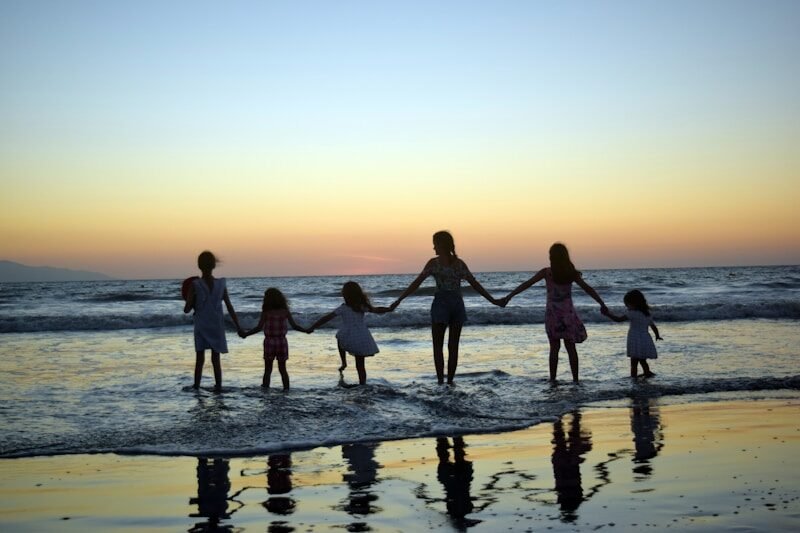convivencia familiar, decalogo de conexion, conexion familair, a family holding hands on the beach at sunset