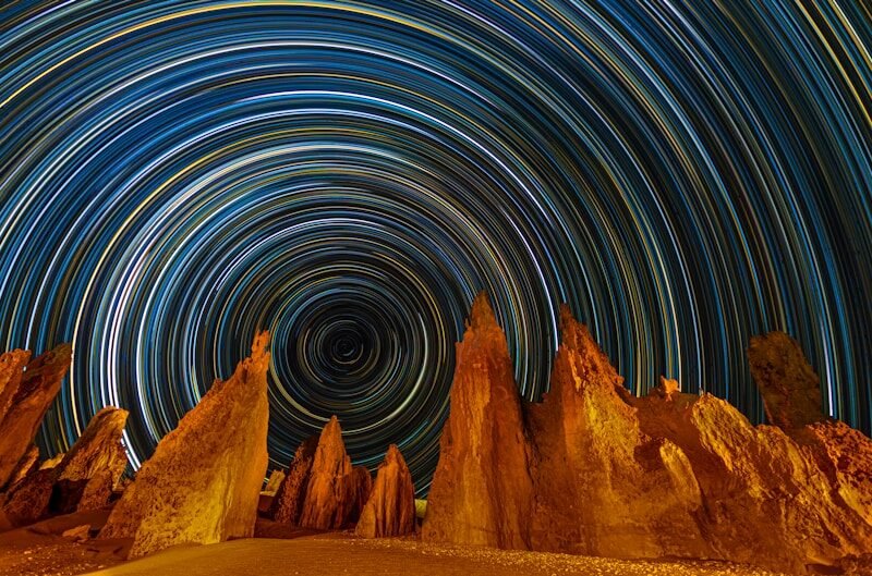 nuestros pensamientos,Star trails circle above desert rock formations.