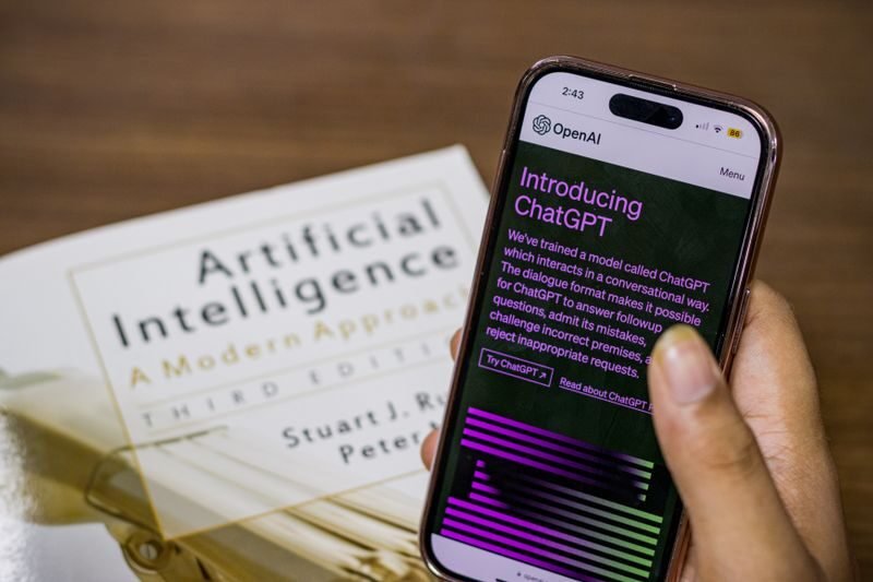 la IA -inteligencia artificia. la IA, IA generativa , inteligencia artificial, Close-up of a smartphone displaying ChatGPT app held over AI textbook.